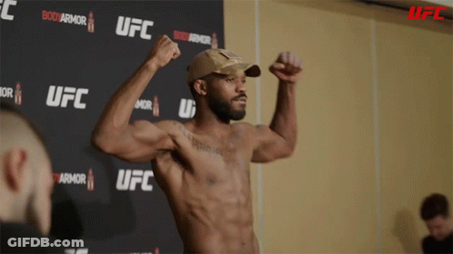 Man Flexing Muscles In Front Of UFC Sign GIF