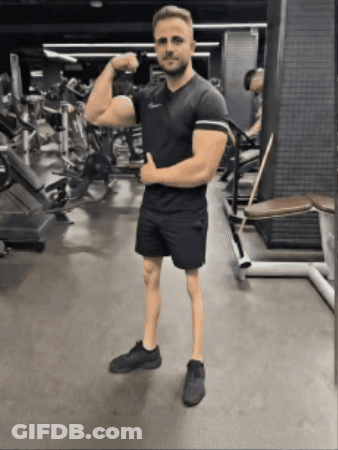 Man Flexing Muscles In Gym While Wearing Shorts GIF