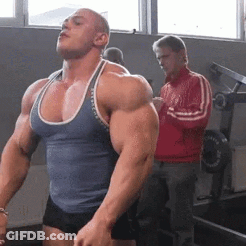 Man Flexing Muscles While Man In Red Jacket Watches GIF