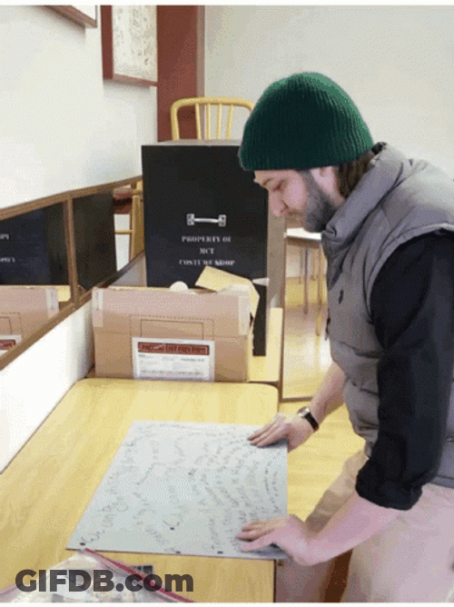 Man Folding Completed Jigsaw Puzzle GIF