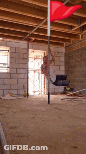 Man Hanging Upside Down On Pole With Red Flag GIF