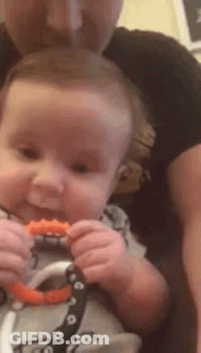 Man Holding Baby Chewing Teething Toy GIF