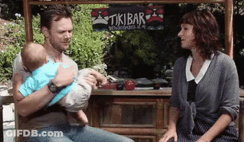 Man Holding Baby In Front Of Tikibar GIF