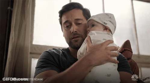 Man Holding Baby With NBC Logo Behind GIF