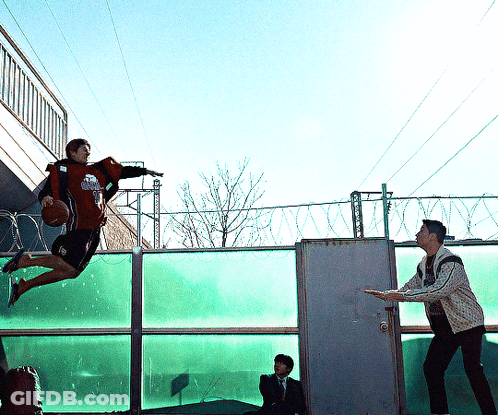 Man Holding Basketball Jumping Over Fence GIF