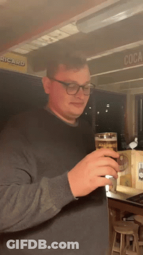 Man Holding Beer In Front Of Ricard Sign GIF