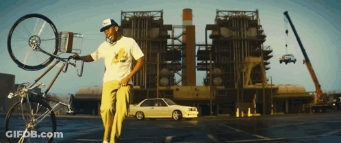 Man Holding Bicycle In Front Of Building With Parked Car GIF