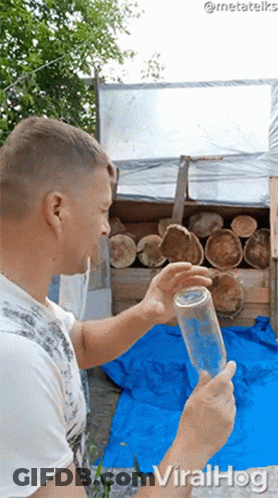 Man Holding Bottle In Front Of Logs With Viralhog GIF
