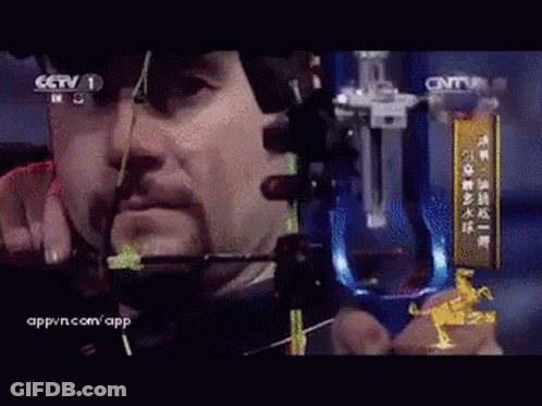 Man Holding Bow And Arrow In Front Of CCTV Sign GIF