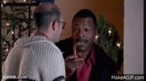 Man Holding Candy Cane In Mouth Talking To Another Man GIF