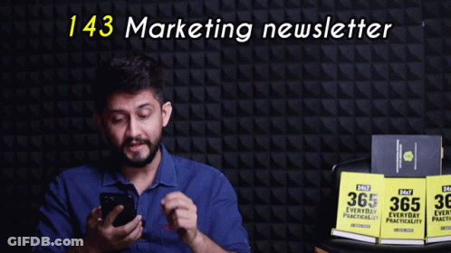Man Holding Cell Phone In Front Of 143 Marketing Newsletter GIF