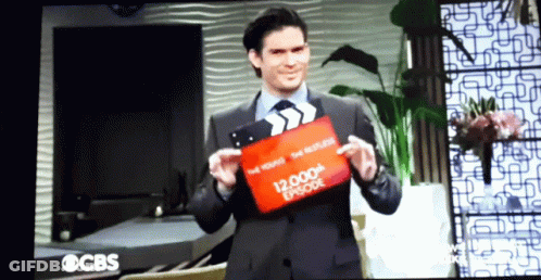 Man Holding Clapper Board Saying 12,000Th Episode GIF