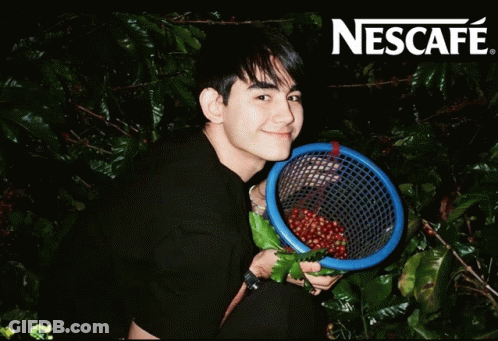 Man Holding Coffee Beans In Front Of Nescafe Sign GIF