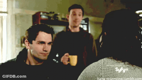 Man Holding Coffee In Front Of Syfy Logo GIF