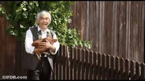 Man Holding Dog In Front Of Fence GIF