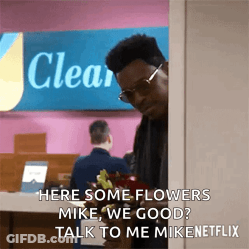Man Holding Flowers In Front Of Sign GIF