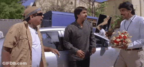Man Holding Flowers Talking To Two Men GIF