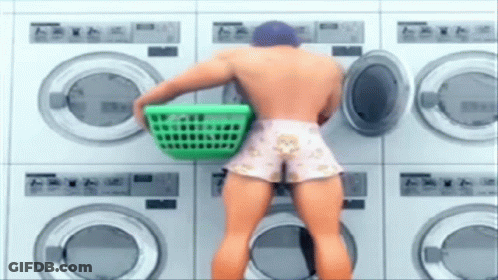Man Holding Green Laundry Basket At Laundromat GIF