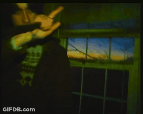 Man Holding Gun In Dark Room With SS Graffiti GIF