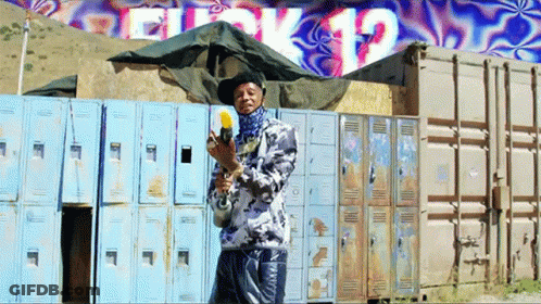 Man Holding Gun In Front Of Block 12 Wall GIF