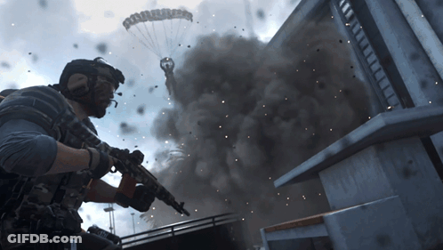 Man Holding Gun In Front Of Building With Smoke And Parachute GIF