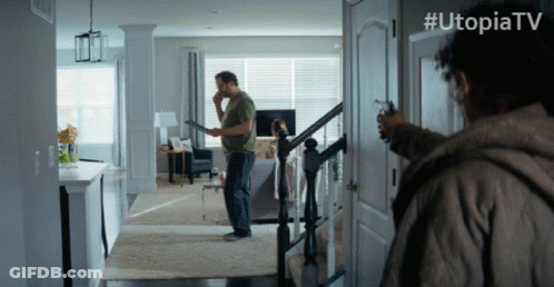 Man Holding Gun In Front Of Door With Utopiatv GIF