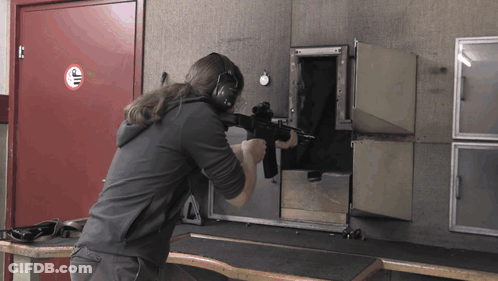 Man Holding Gun In Front Of No Smoking Sign GIF