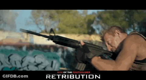 Man Holding Gun In Front Of Retribution Wall GIF