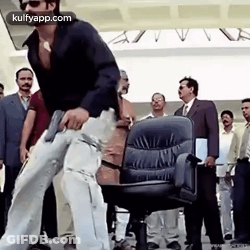 Man Holding Gun Next To Office Chair GIF