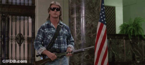 Man Holding Gun Says I Have Come Here To Chew Bubblegum In Front Of American Flag GIF