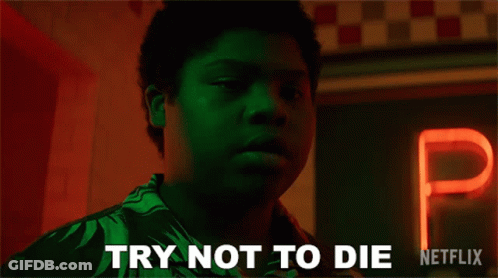 Man Holding Hot Dog By Try Not To Die Sign GIF