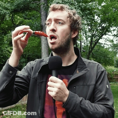 Man Holding Microphone Eating Red Pepper GIF