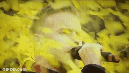 Man Holding Microphone In Field Of Yellow Papers GIF