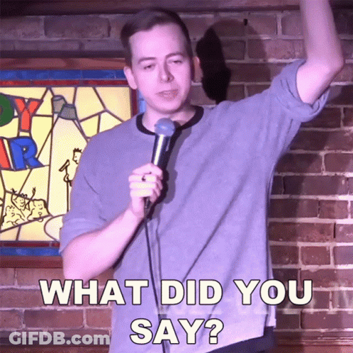 Man Holding Microphone In Front Of Brick Wall Saying What Did You Say GIF