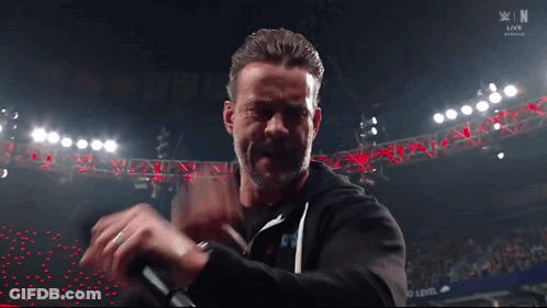 Man Holding Microphone In Front Of WWE Live Sign GIF