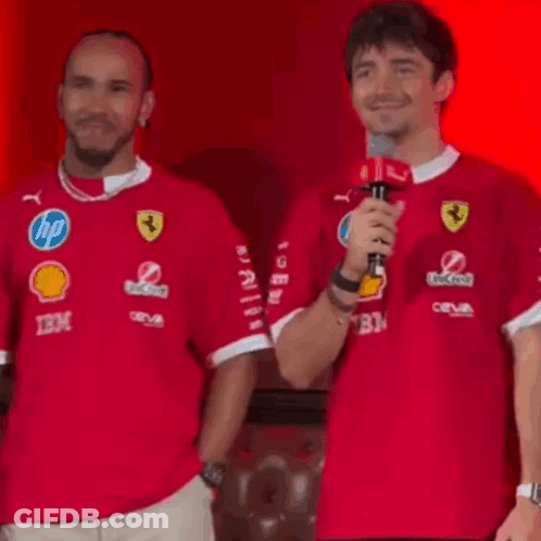 Man Holding Microphone Next To Man In Red Shirt GIF