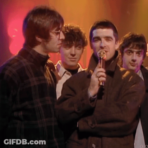 Man Holding Microphone Next To Two Men GIF
