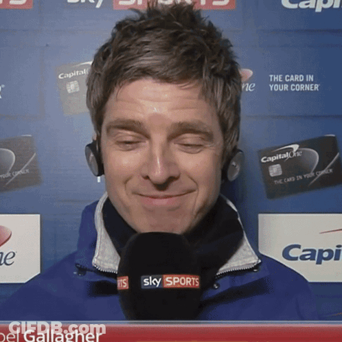 Man Holding Microphone Next To Two Men GIF