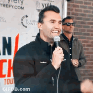 Man Holding Microphone Smiling In Front Of Turning Point Sign GIF