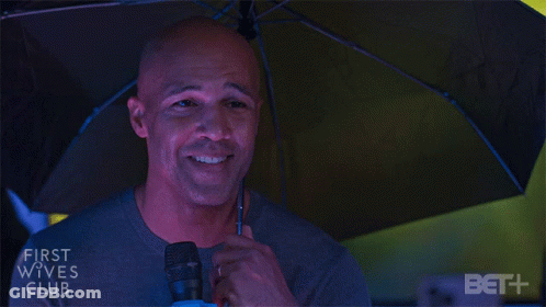 Man Holding Microphone Under First Wives Club Umbrella GIF