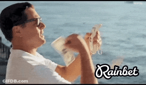 Man Holding Money In Front Of Ocean Rainbet GIF