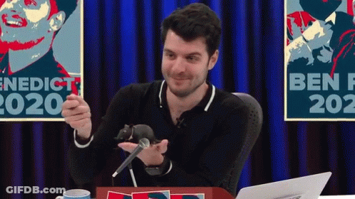 Man Holding Mouse At Microphone At Table With Laptop GIF