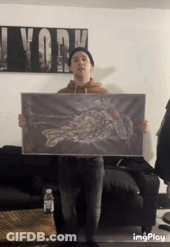 Man Holding Painting With Work On Wall GIF