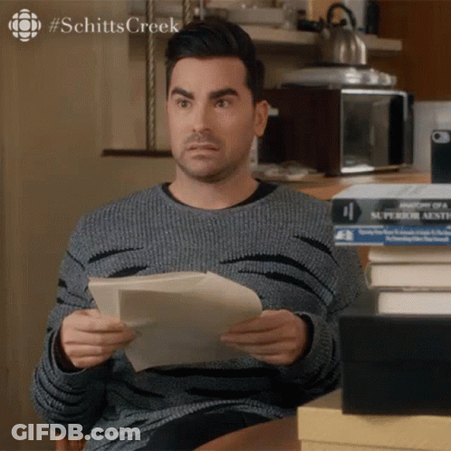 Man Holding Paper In Front Of Books Schitts Creek GIF