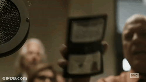 Man Holding Paper Saying A.M.C. In Front Of Speaker GIF