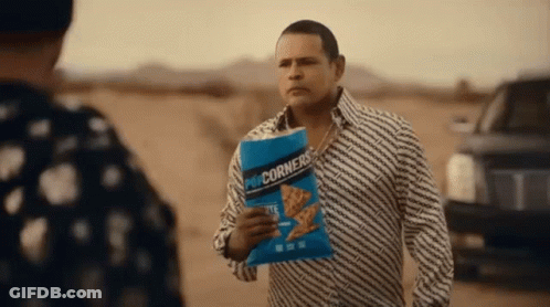 Man Holding Popcorn Talking To Another In Desert GIF