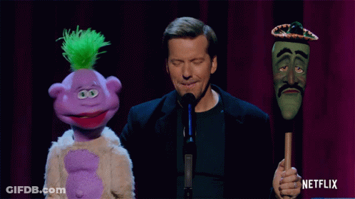 Man Holding Purple And Green Puppets With Sombrero GIF