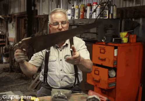 Man Holding Saw In Front Of Orange Filing Cabinet With Letter D GIF