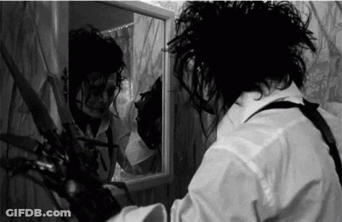 Man Holding Scissors In Front Of Mirror GIF