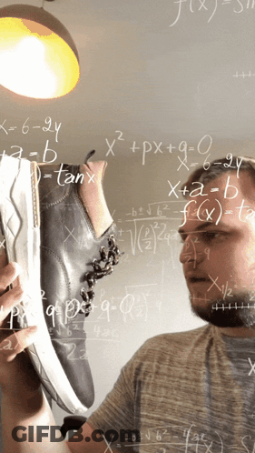 Man Holding Shoes In Front Of Chalkboard With Math Equations GIF